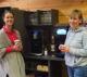 Zwei Kolleginnen genießen eine Kaffeepause neben einem Kaffeevollautomaten und Wasserspender im Büro von AWEWA Coaching