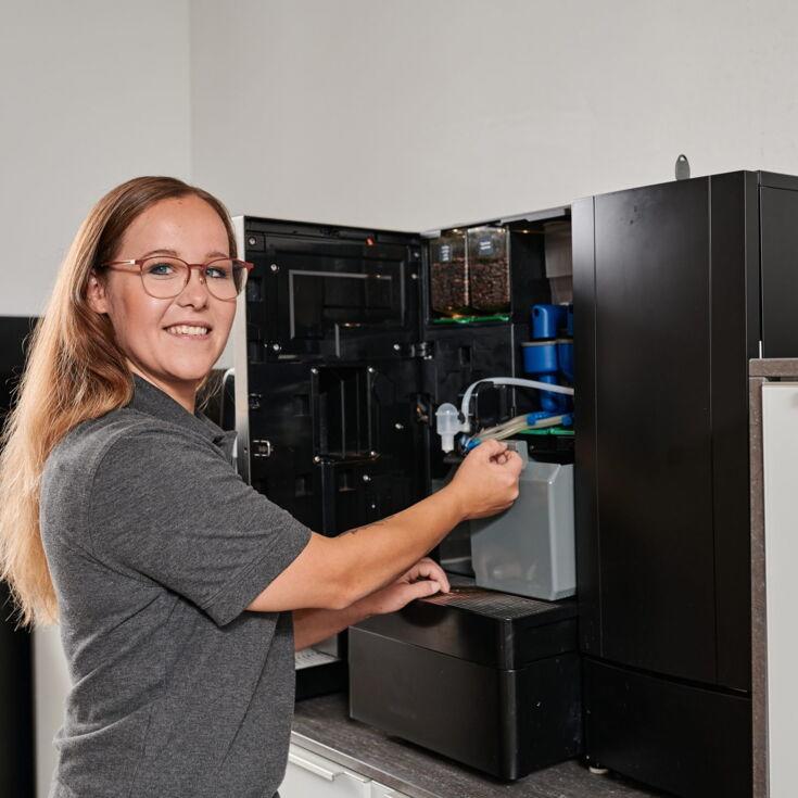 Mitarbeiterin aus dem technischen Aussendienst zieht den Wassertank raus Technischer Aussendienst bei Kaffee Partner